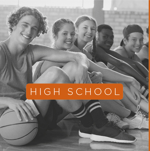 High schoolers sitting on a court with a basketball